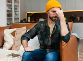 Free photo man sitting on sofa and having a headache