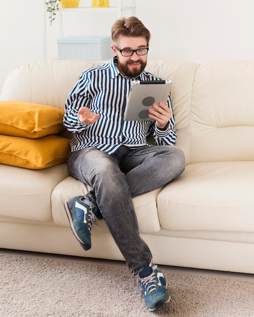 Uomo seduto sul divano di casa con tablet