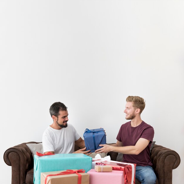 Man sitting on sofa taking gift box against white background