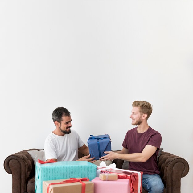 Человек, сидя на диване, принимая подарочной коробке на белом фоне