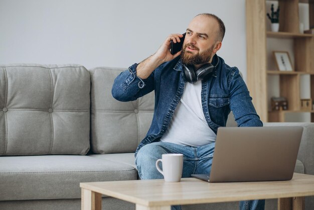 Man sitting on sofa and working from home on his laptop