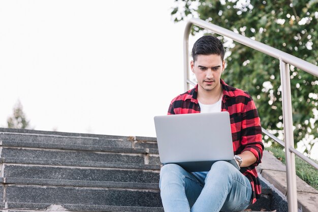 Man sitting on staircase using laptop