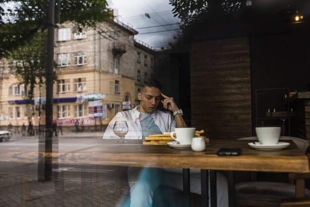 Человек, сидящий за столом в ресторане, видно из оконного стекла