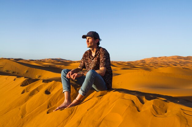 사막에서 모래 언덕 위에 앉아 남자