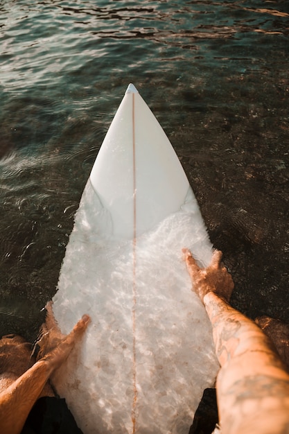 Man sitting on white surfboard in sea 