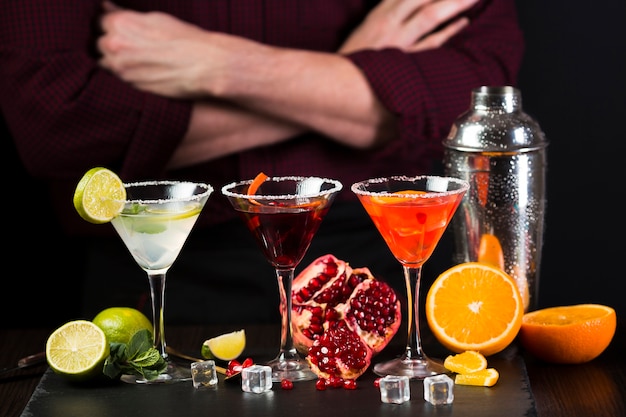 Man sitting with arms crossed behind colorful cocktail glasses