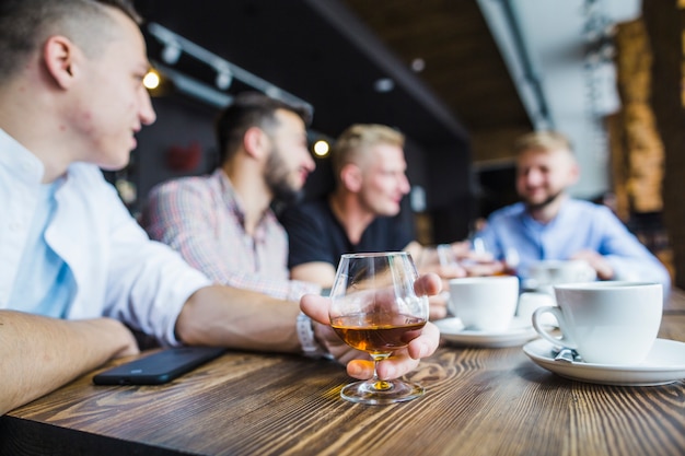 Man sitting with his friends in the restaurant holding drink