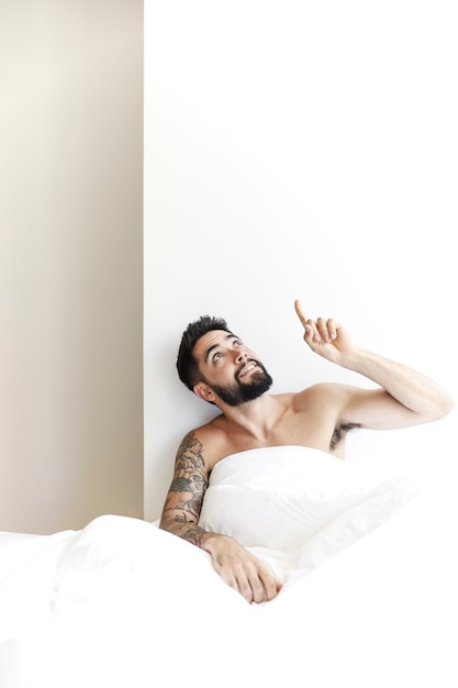 Man sitting with white blanket pointing upward