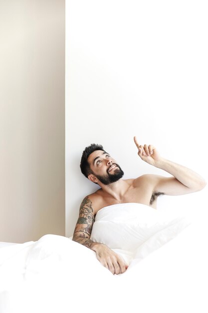 Man sitting with white blanket pointing upward