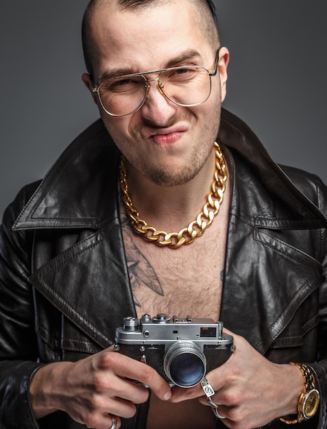 Man in skin coat holding photo camera. Isolated on grey.