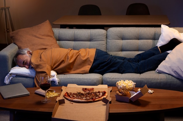 Мужчина спит дома на диване после еды на вынос