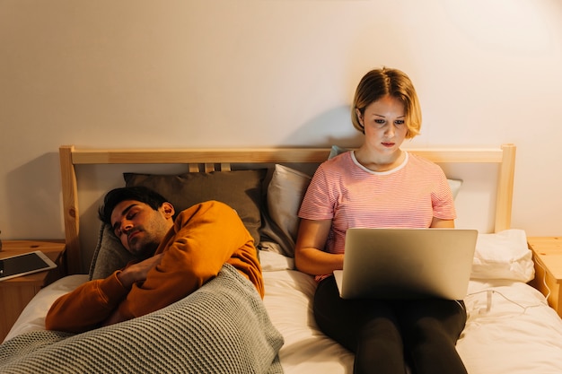 Man sleeping near woman with laptop