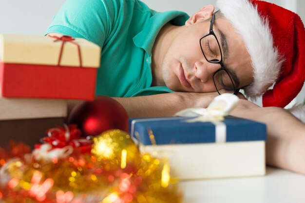 Man sleeping on table with Christmas gifts and baubles