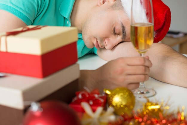 Man sleeping on table with Christmas gifts and champagne glass