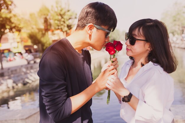 彼のガールフレンドは彼を見ながら、男はバラを嗅ぎます