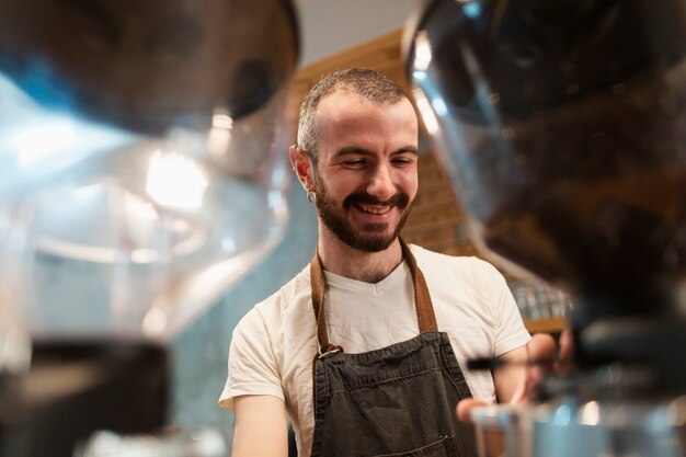 エプロンに笑みを浮かべて、コーヒーを作る男