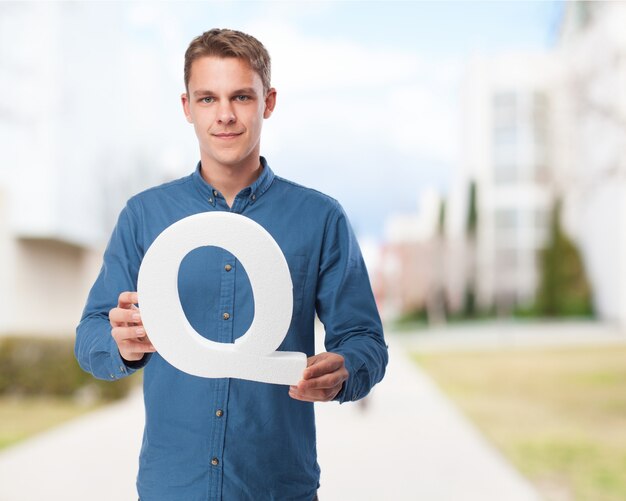 Man smiling holding the letter "q"