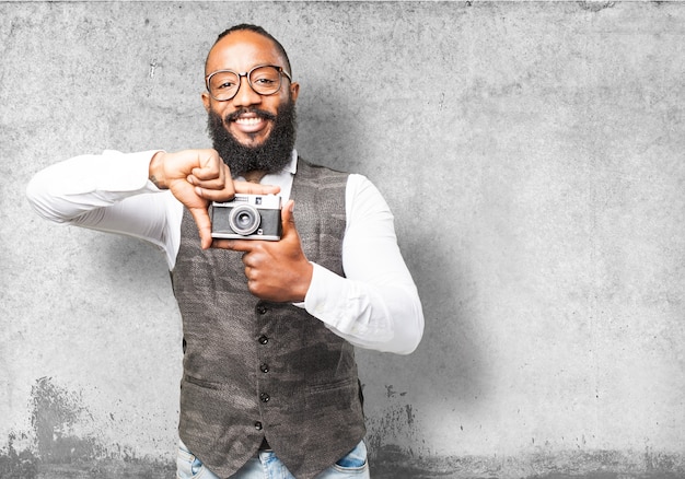 Man smiling and holding an old camera with his fingers
