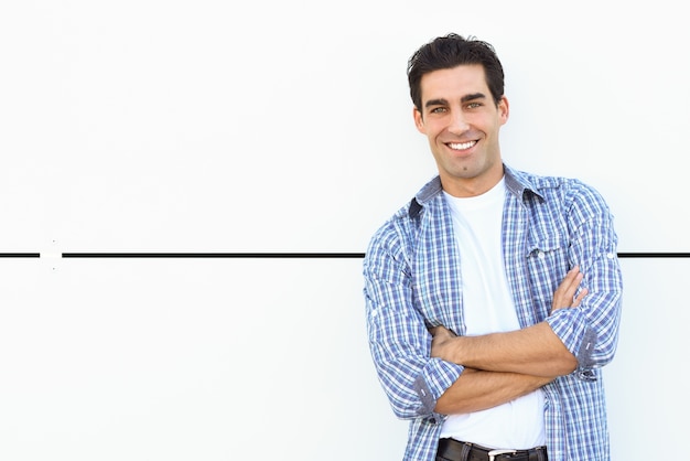 Man smiling leaning against a white wall