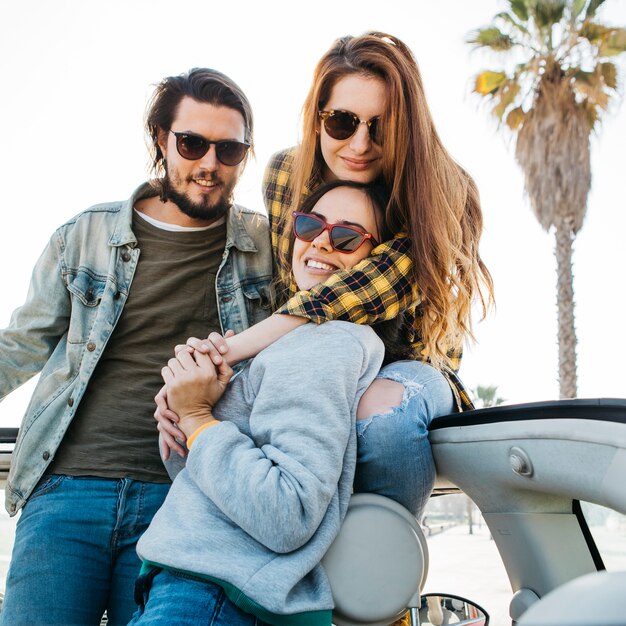 Man and smiling women hugging and leaning out from auto