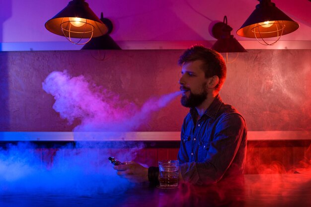 The man smoke an electronic cigarette at the vape shop. Vape bar.