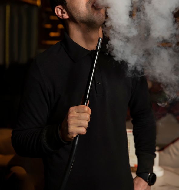 Free photo man smokes shisha and withdraw the smoke