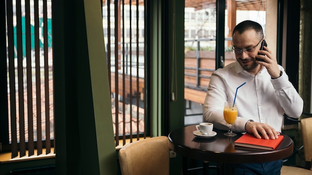 Free photo man speaking on phone in cafe