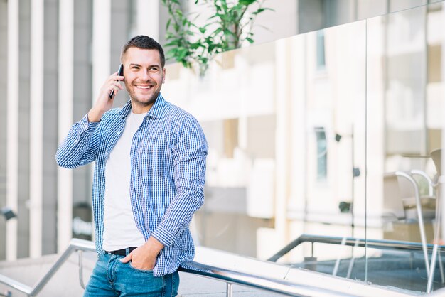 Man speaking on phone near glass fence