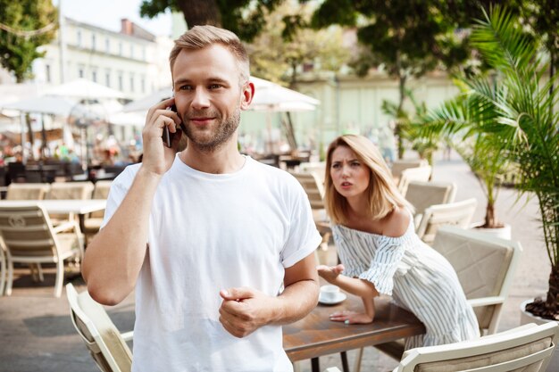 그의 여자 친구가 지루해하는 동안 전화로 말하는 남자.