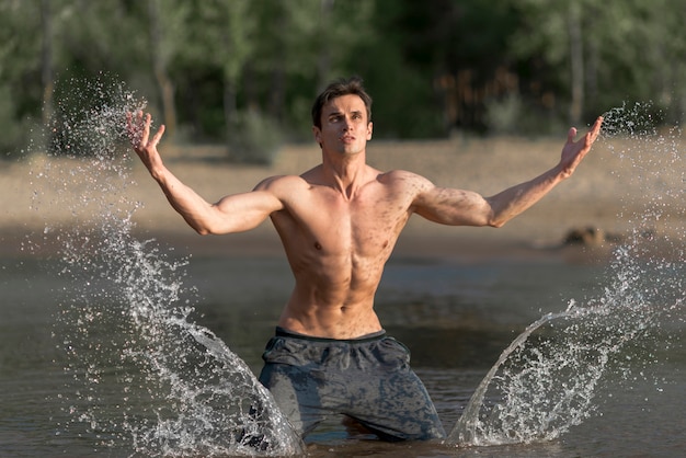 Foto gratuita uomo che spruzza acqua in spiaggia