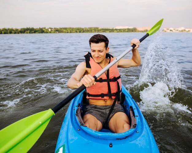 Man splashing water with paddle while kayaking on lake