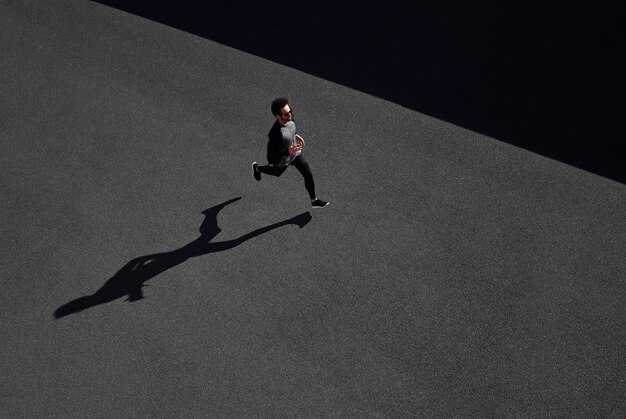 Man in sportswear running on road top view