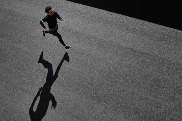 Foto gratuita uomo in abiti sportivi in esecuzione su strada