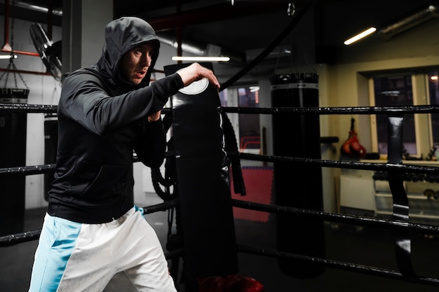 Man in sportswear training in boxing ring with copy space