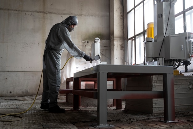 Free photo man spraying powder paint from a gun full shot