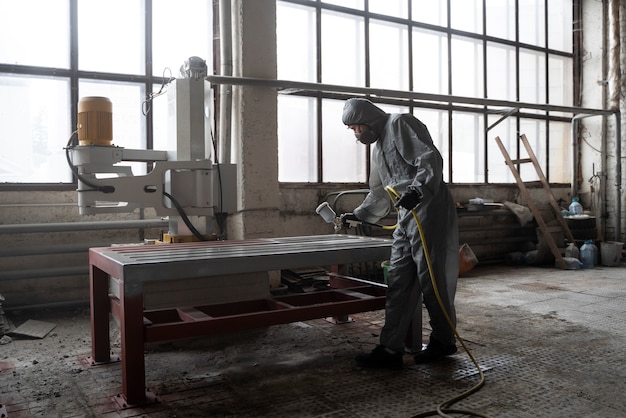 Free photo man spraying powder paint from a gun full shot