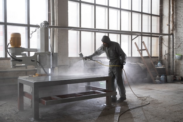 Free photo man spraying powder paint from a gun full shot