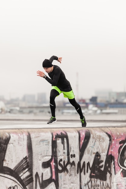 Free photo man sprinting on rooftop on a rainy day