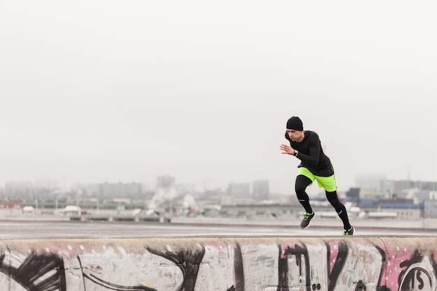 Free photo man sprinting on rooftop