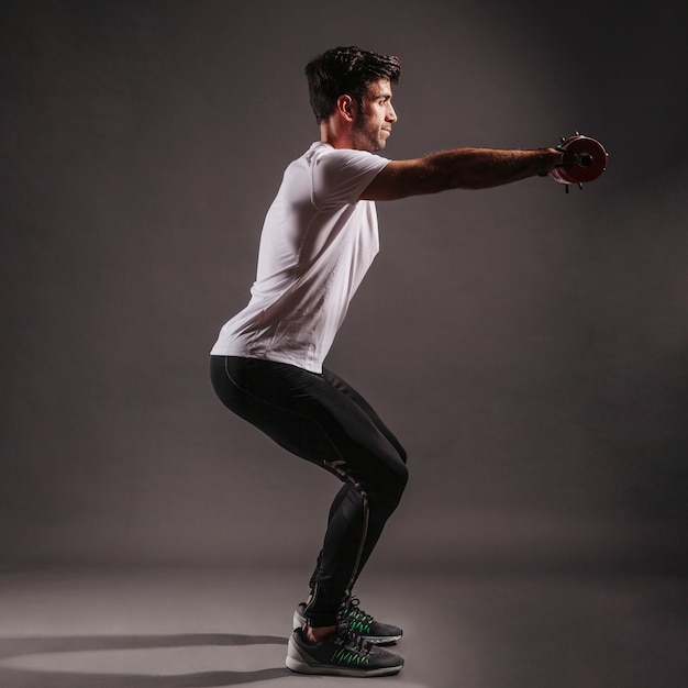 Man squatting with dumbbells