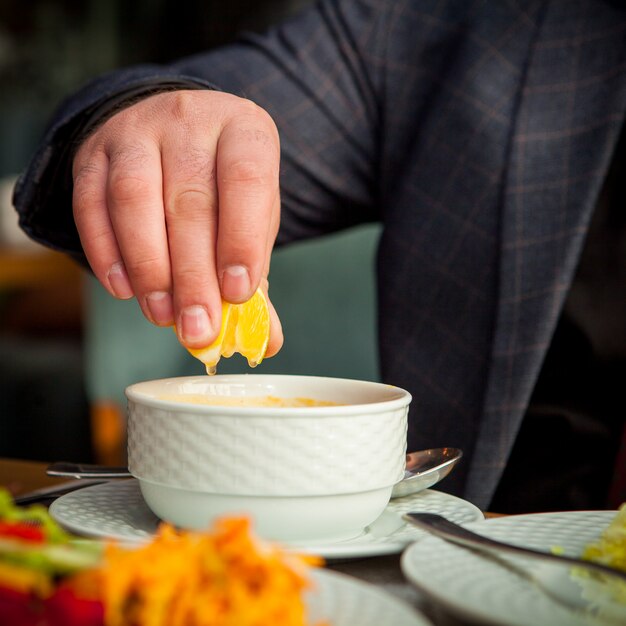 Man squeezes lemon into soup