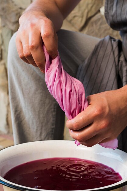 Man squeezing cloth from pink natural pigment