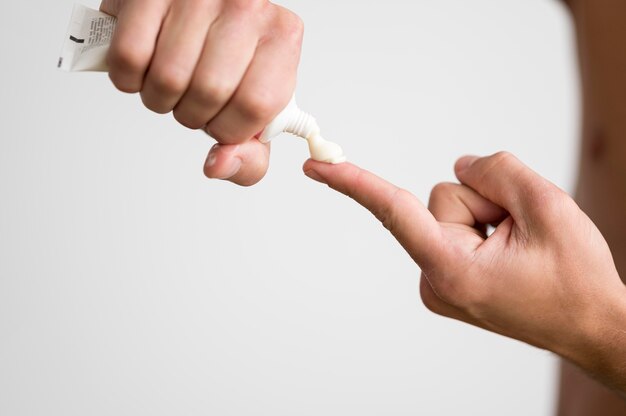 Man squeezing cream from tube on his finger