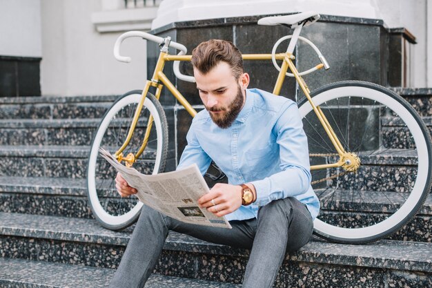 Man on stairs reading newspaper