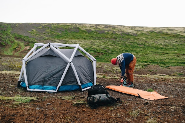 Человек стоит рядом с современной палаткой в исландии