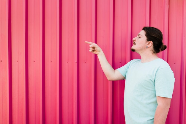 Man standing against red shutter pointing finger to side