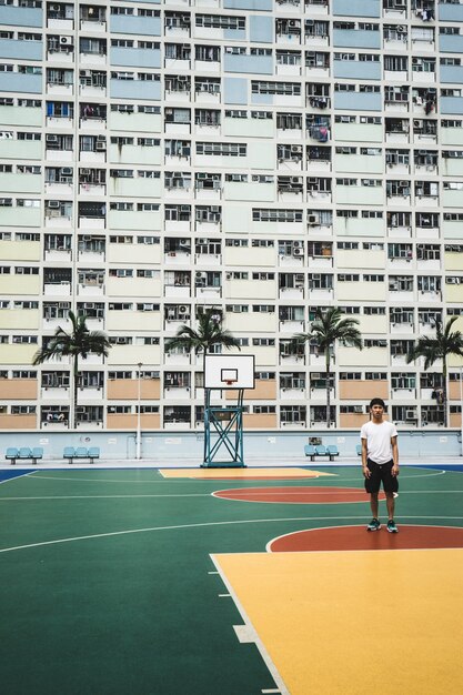 建物の近くのバスケットボールコートに立っている男