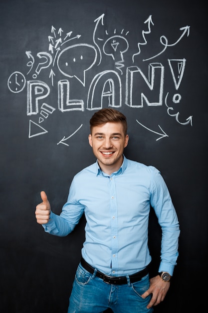 Man standing over blackboard with a plan concept thumbs up