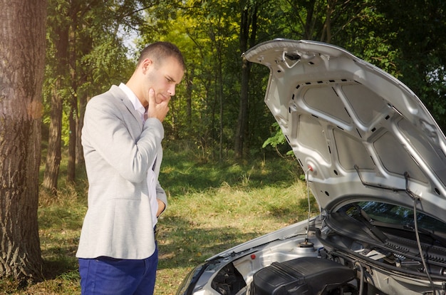 Free photo man standing by the open hood trying to fix the vehicle