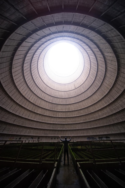 Foto gratuita uomo in piedi in una sala vuota con una finestra rotonda sul soffitto